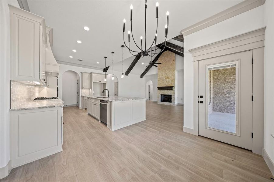 Kitchen with ceiling fan, open floor plan, stainless steel appliances, arched walkways, and a fireplace Kitchen with ceiling fan, open floor plan, stainless steel appliances, arched walkways, and a fireplace