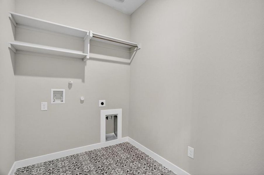 Dedicated laundry area featuring patterned tile flooring, light gray walls, built-in shelving, and a hanging rod Dedicated laundry area featuring patterned tile flooring, light gray walls, built-in shelving, and a hanging rod