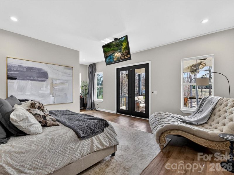 Spacious primary suite featuring elegant finishes, a cozy sitting area, and direct access to outdoor views through French doors.
