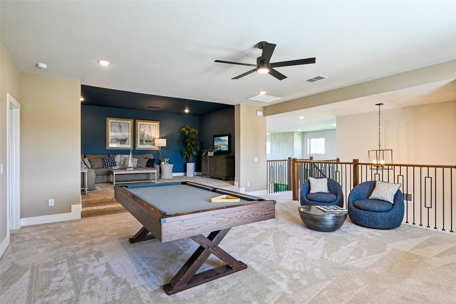 Upstairs game room with pool table, blue accent wall, seating area, and open staircase railing Upstairs game room with pool table, blue accent wall, seating area, and open staircase railing