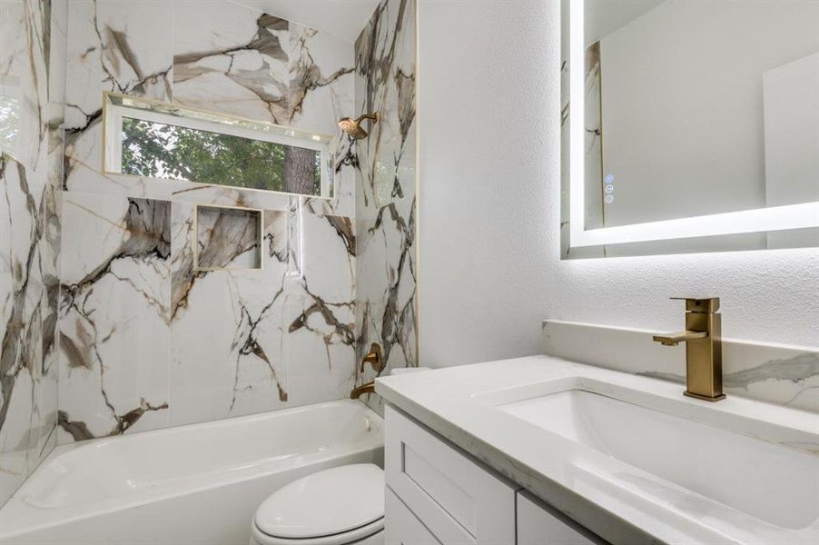 Full bathroom with a combined bath / shower with marble appearance, vanity, and a textured wall Full bathroom with a combined bath / shower with marble appearance, vanity, and a textured wall