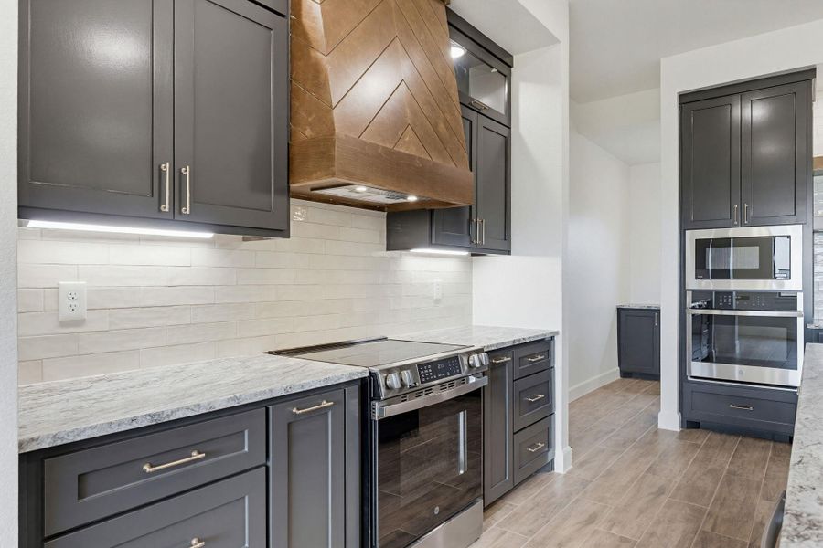 A contemporary kitchen features sleek gray cabinetry and premium stainless steel appliances. A contemporary kitchen features sleek gray cabinetry and premium stainless steel appliances.