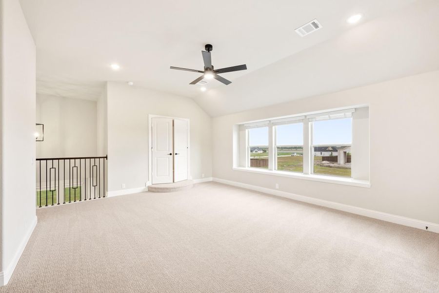 Spacious upstairs bonus room with vaulted ceiling, ceiling fan, carpet flooring, and large windows overlooking neighborhood