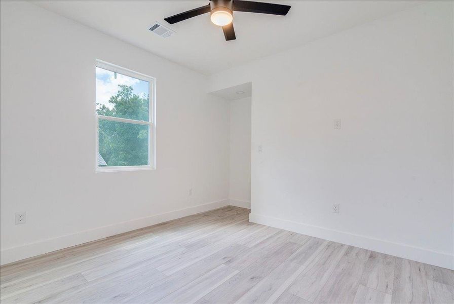 Empty room with light wood-style flooring and ceiling fan