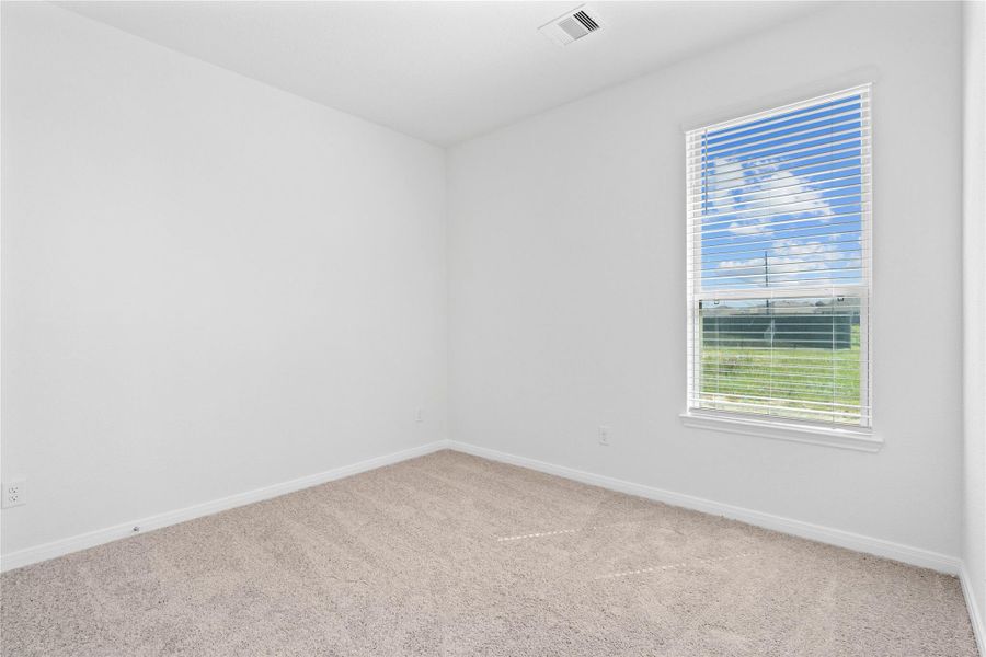 This secondary bedroom offers comfort and style with plush carpeting, neutral paint tones, recessed lighting, a large window with blinds, and a generously sized closet.