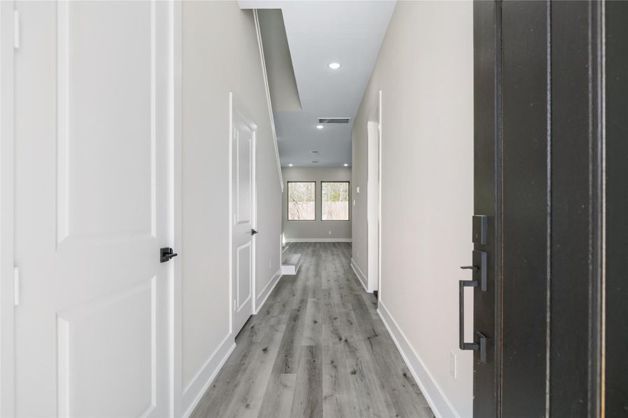 Stepping into your new home, you're greeted by a bright and inviting entryway that draws you in. Clean white walls, stylish finishes, and abundant natural light create a warm welcome. Gaze down the hallway to the expansive windows at the back, offering a glimpse of the fenced-in yard — the perfect backdrop for everyday living