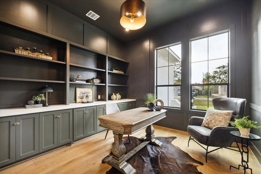Stylish study with custom built-ins, tall windows, and rich designer finishes.