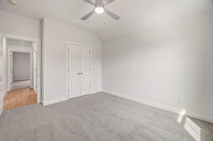 Unfurnished bedroom featuring light carpet, vaulted ceiling, ceiling fan, and a closet Unfurnished bedroom featuring light carpet, vaulted ceiling, ceiling fan, and a closet