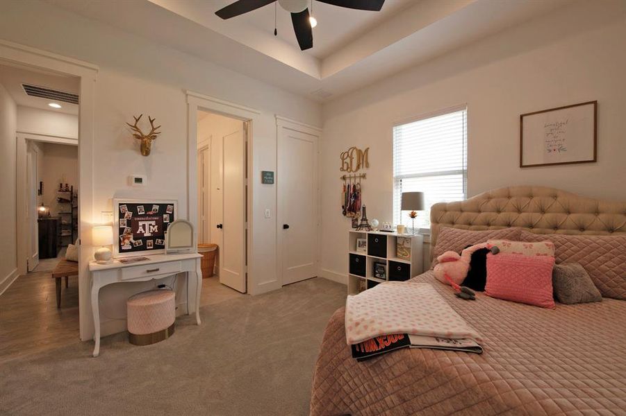 Bedroom with carpet flooring, a tray ceiling, and ceiling fan