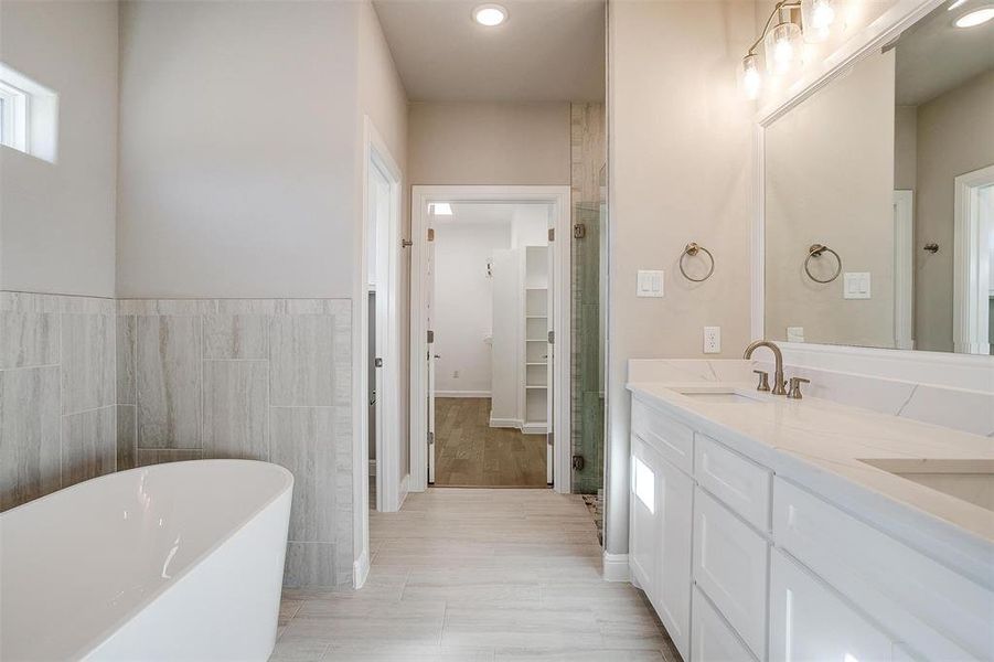 Bathroom featuring tile walls, vanity, and a tub