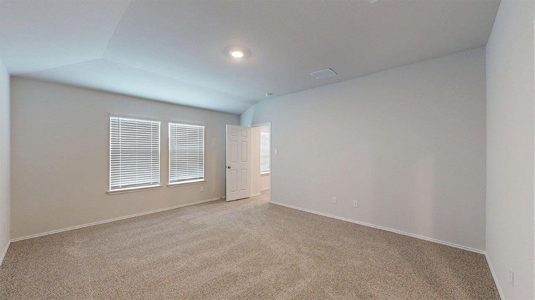 Spacious room featuring vaulted ceilings, neutral-toned carpet, two windows with blinds, a recessed ceiling light, and a white paneled door Spacious room featuring vaulted ceilings, neutral-toned carpet, two windows with blinds, a recessed ceiling light, and a white paneled door