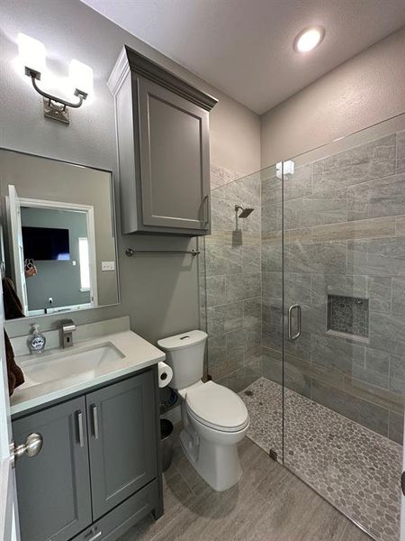 Bathroom featuring vanity, a shower stall, light wood-style flooring, and a textured ceiling