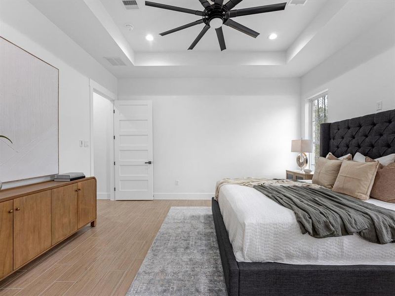 Primary bedroom features include; ceiling fan, tray ceiling, and tile flooring