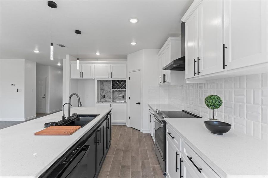 Kitchen featuring stainless steel range with electric stovetop, sink, decorative backsplash, and white cabinetry