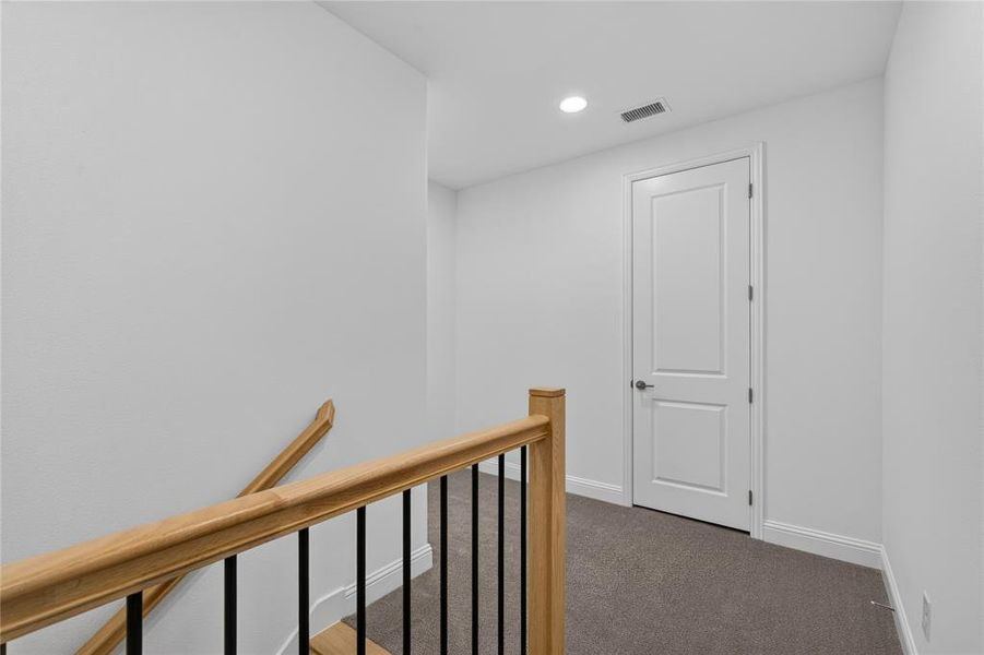Upper-level landing featuring light-colored walls, recessed ceiling lighting, and a paneled door Upper-level landing featuring light-colored walls, recessed ceiling lighting, and a paneled door