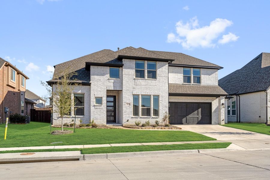 Two-story home with light brick exterior, two-car garage, and green front lawn Two-story home with light brick exterior, two-car garage, and green front lawn