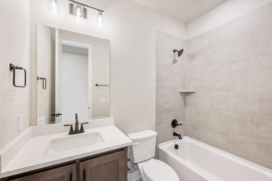 Bathroom with single vanity, white countertop, tiled tub-shower combo, and dark bronze fixtures