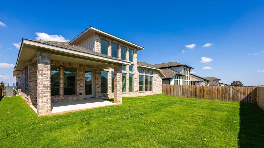 Rear view of property featuring a fenced backyard, a patio area, brick siding, and roof with shingles
