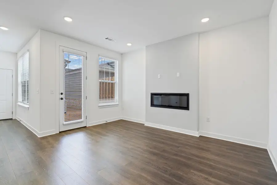 Spacious room featuring wood-finish flooring, recessed lighting, and white baseboards