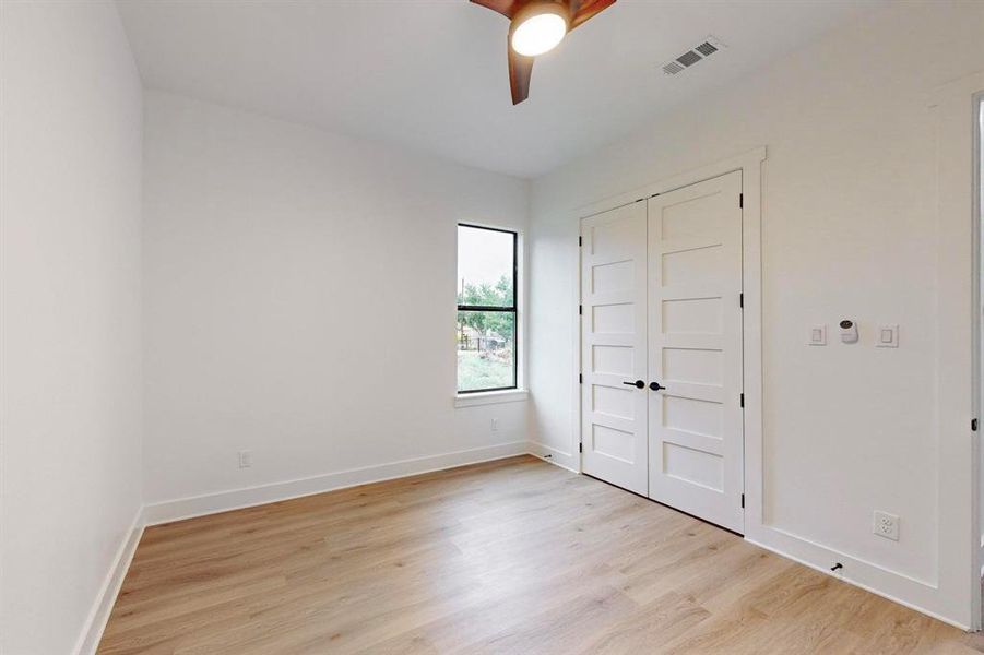 Room featuring wood-finish flooring, white baseboards, and bright white walls Room featuring wood-finish flooring, white baseboards, and bright white walls