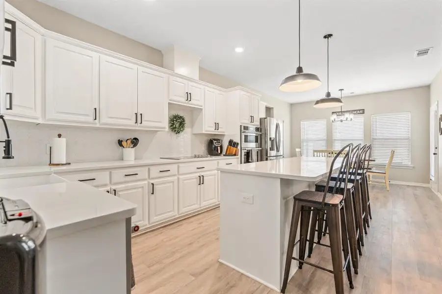 Kitchen featuring an island, decorative backsplash, a center island, hanging light fixtures, and white cabinets Kitchen featuring an island, decorative backsplash, a center island, hanging light fixtures, and white cabinets