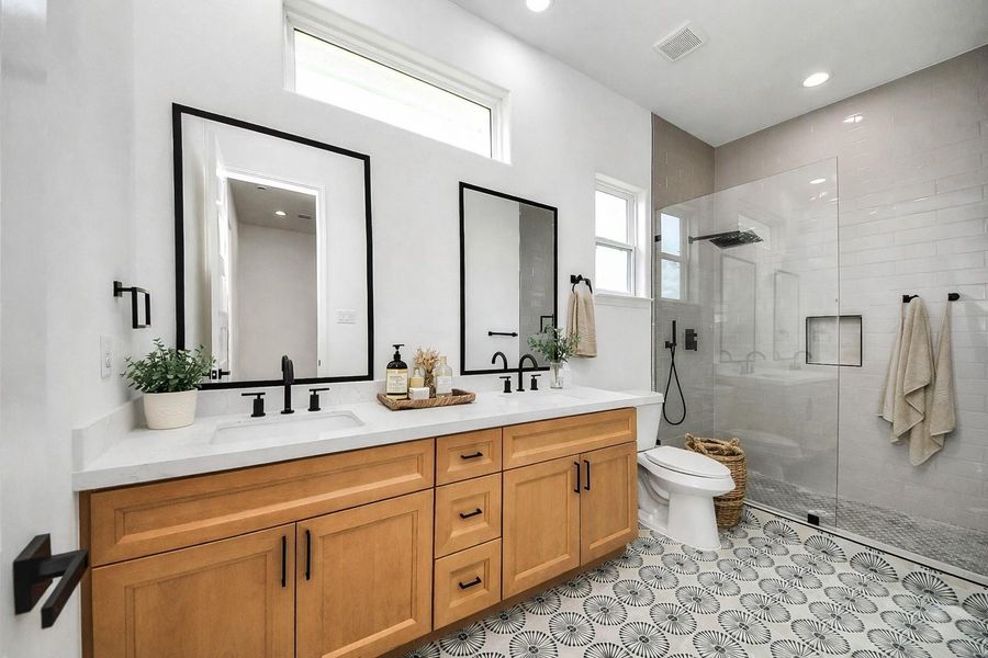 Spacious guest bathroom featuring a dual-sink vanity, modern finishes, and a full walk-in shower with sleek tile work. A bright and well-designed space that offers both comfort and convenience for guests.