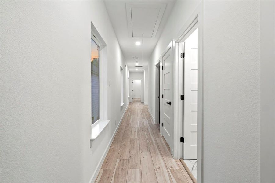 Hall with attic access, light wood finished floors, and baseboards Hall with attic access, light wood finished floors, and baseboards