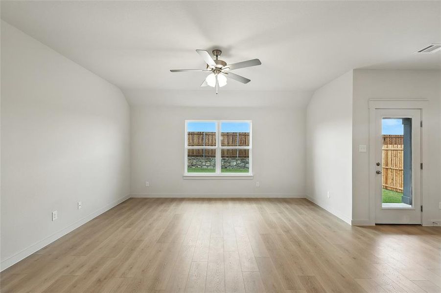 Unfurnished living room with plenty of natural light, light wood-style floors, vaulted ceiling, and ceiling fan Unfurnished living room with plenty of natural light, light wood-style floors, vaulted ceiling, and ceiling fan