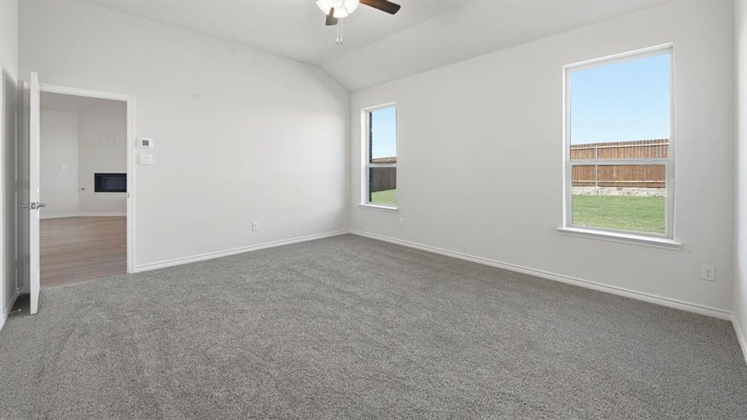 Empty room with vaulted ceiling, carpet flooring, and ceiling fan Empty room with vaulted ceiling, carpet flooring, and ceiling fan