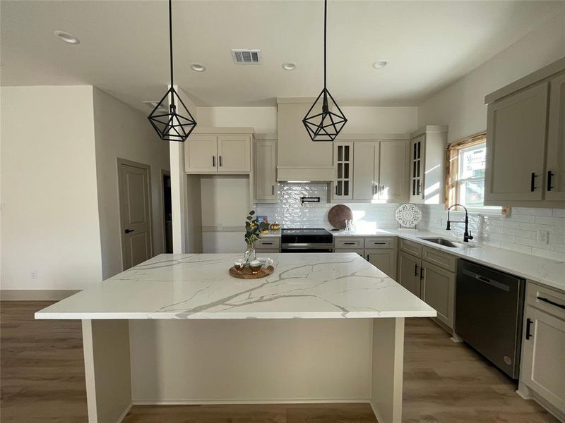 Kitchen featuring light stone countertops, appliances with stainless steel finishes, a center island, and sink