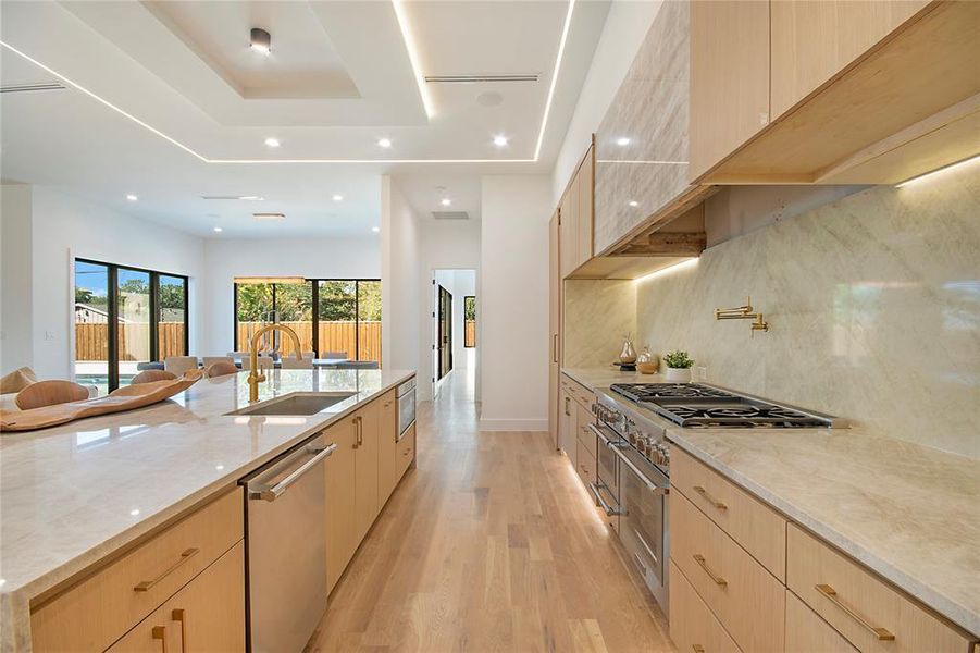 Kitchen featuring light brown cabinets, light stone countertops, modern cabinets, and recessed lighting