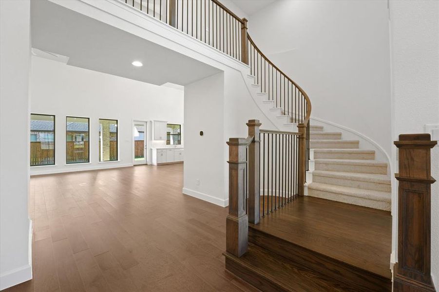 Stairway featuring a towering ceiling, wood finished floors, and recessed lighting