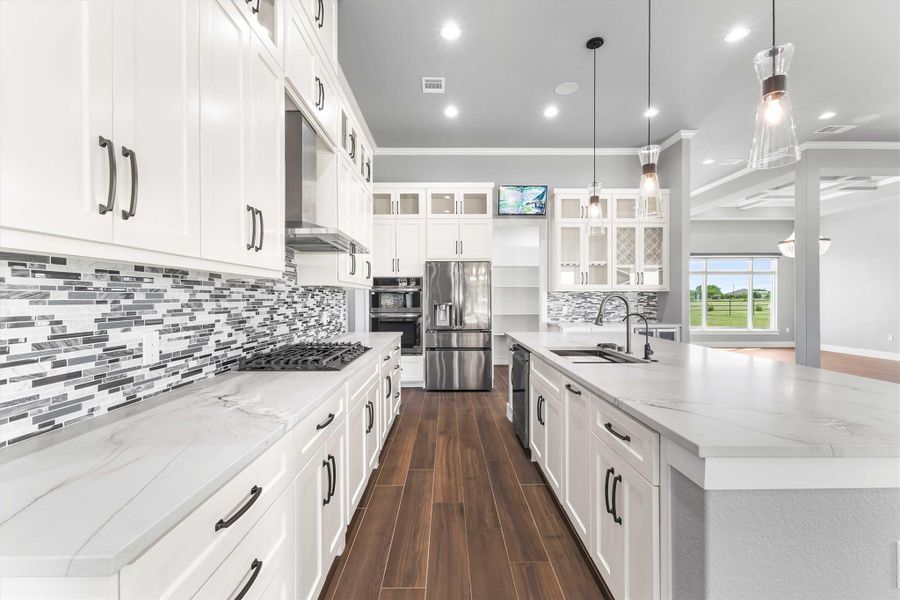 Kitchen with appliances with stainless steel finishes, a sink, a large island with sink, dark wood-style flooring, and wall chimney exhaust hood Kitchen with appliances with stainless steel finishes, a sink, a large island with sink, dark wood-style flooring, and wall chimney exhaust hood