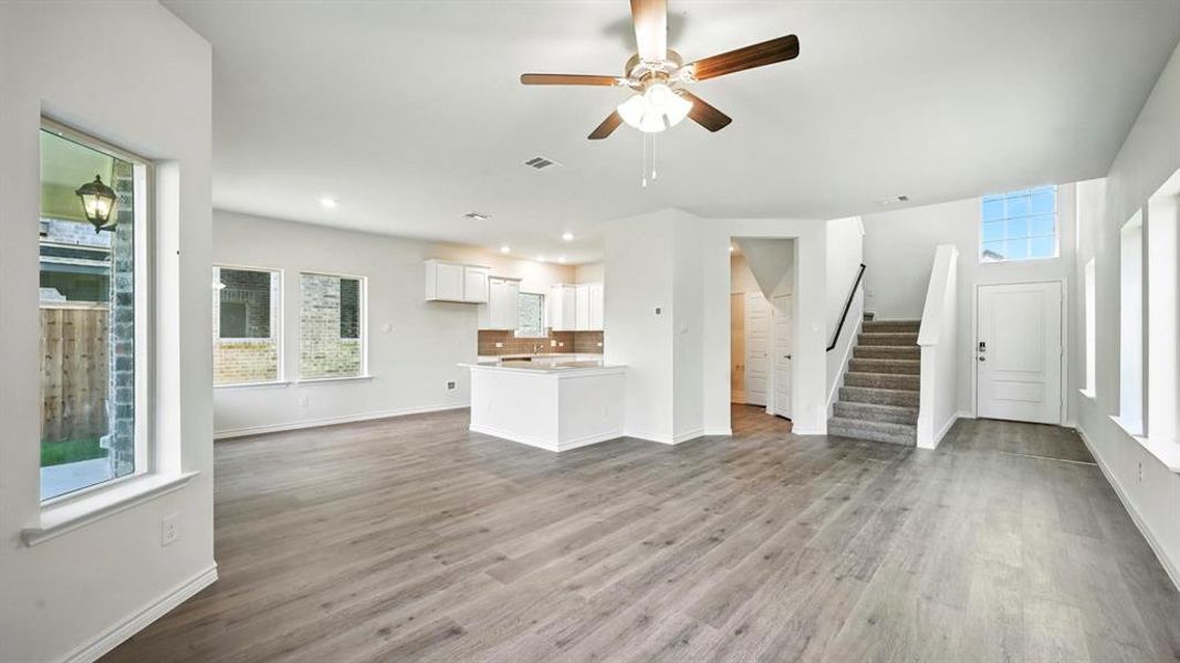 Unfurnished living room featuring healthy amount of natural light, stairs, ceiling fan, dark wood-type flooring, and recessed lighting
