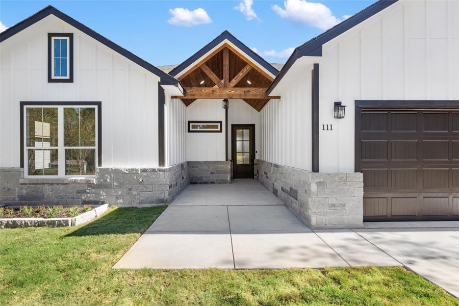 Doorway to property featuring stone siding, board and batten siding, and a lawn