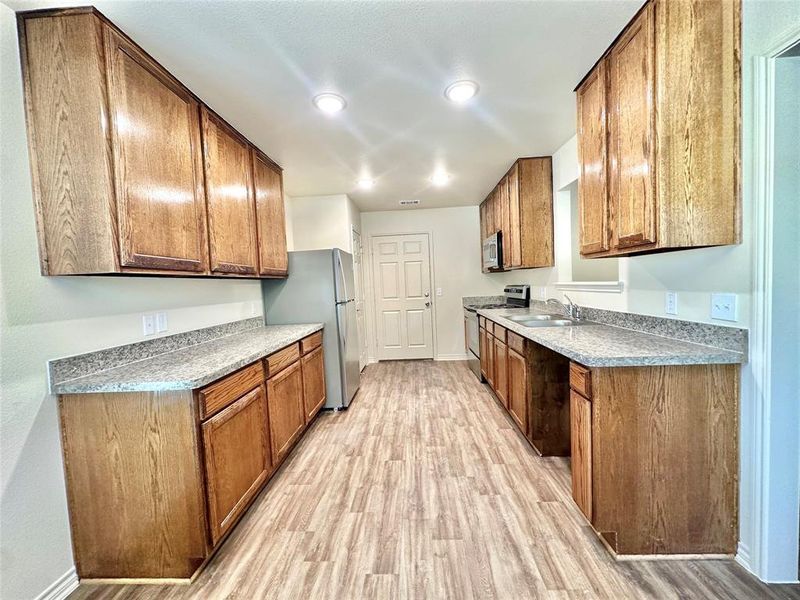 Kitchen with sink, light hardwood / wood-style flooring, and stainless steel appliances