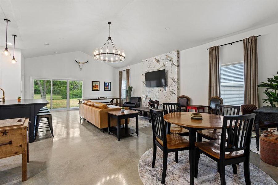 Dining area featuring finished concrete flooring, a chandelier, and plenty of natural light