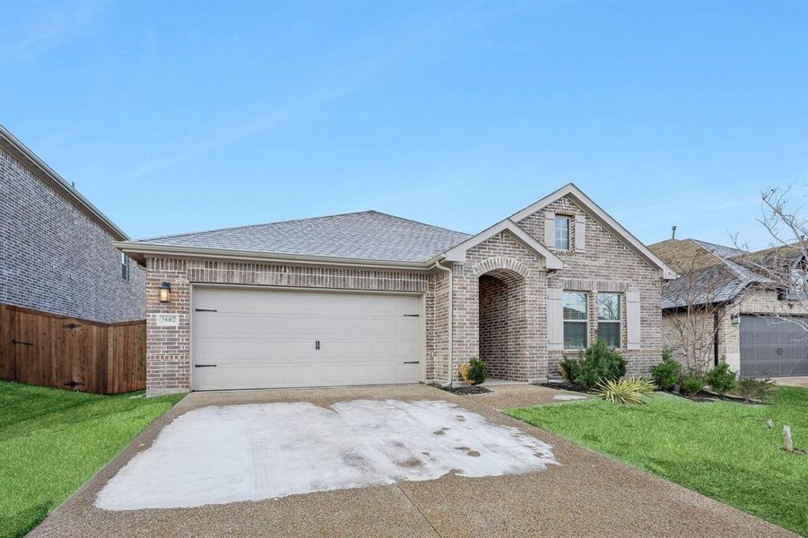 Ranch-style house featuring a garage and a front yard