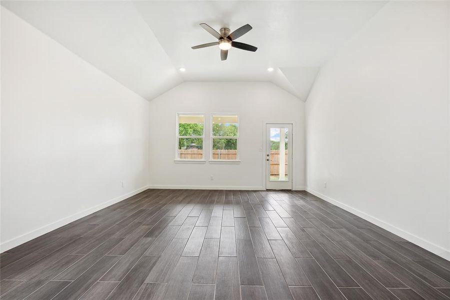 Unfurnished room featuring vaulted ceiling, dark hardwood / wood-style flooring, and ceiling fan