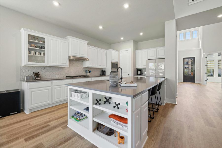 Kitchen featuring stainless steel appliances (fridge does NOT convey) decorative backsplash, a breakfast bar, light wood-type flooring, and recessed lighting Kitchen featuring stainless steel appliances (fridge does NOT convey) decorative backsplash, a breakfast bar, light wood-type flooring, and recessed lighting