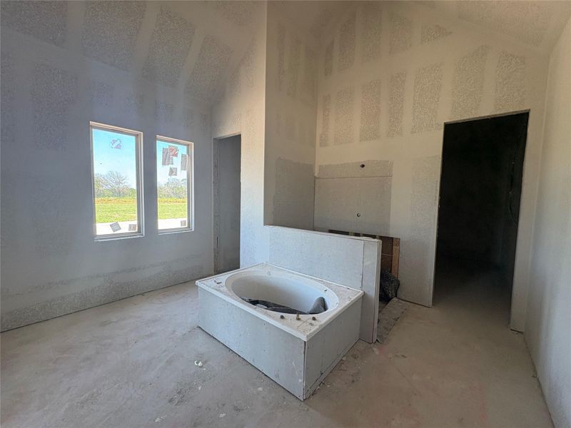 Bathroom featuring a high ceiling and a bath Bathroom featuring a high ceiling and a bath