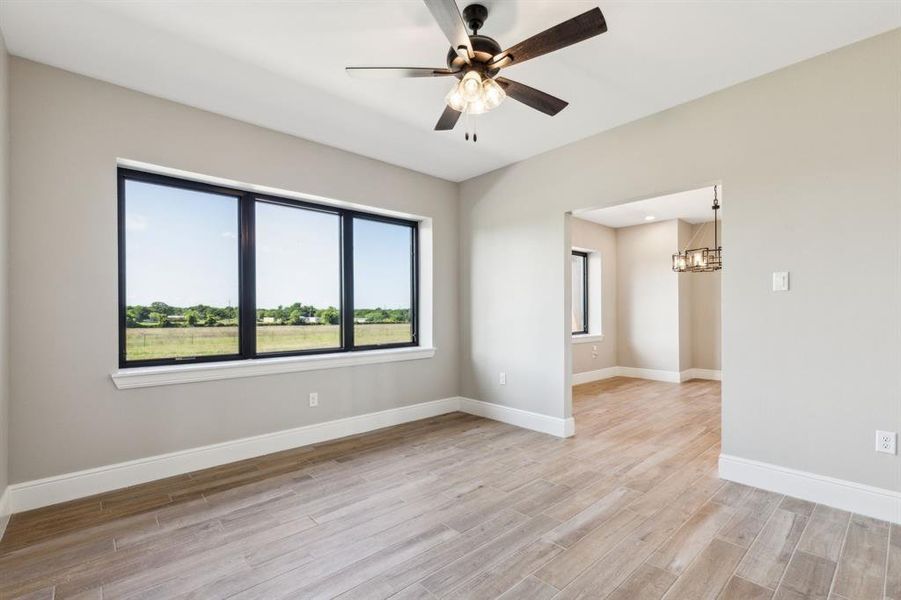 Den featuring natural light, wood look tile floors, baseboards, and ceiling fan. Den featuring natural light, wood look tile floors, baseboards, and ceiling fan.