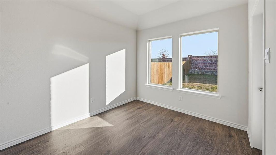Bright interior room featuring wood-finish flooring, white walls, and two large windows Bright interior room featuring wood-finish flooring, white walls, and two large windows