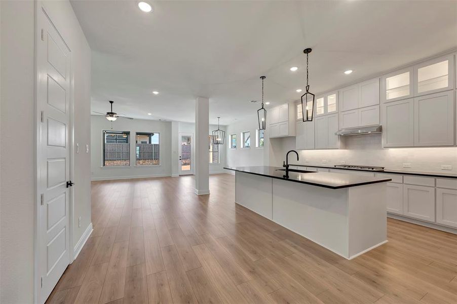 Kitchen with dark countertops, open floor plan, white cabinets, and glass fronted cabinets