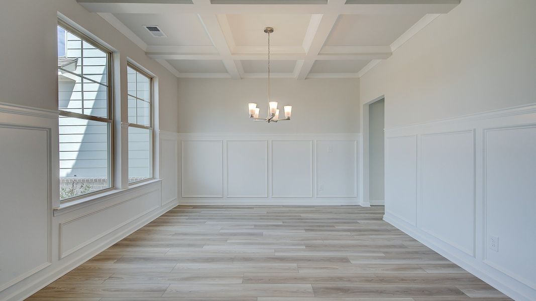 Open dining room with coffered ceiling, chandelier lighting, and LVP flooring in the Clarity at Brighton in Locust Grove, GA.