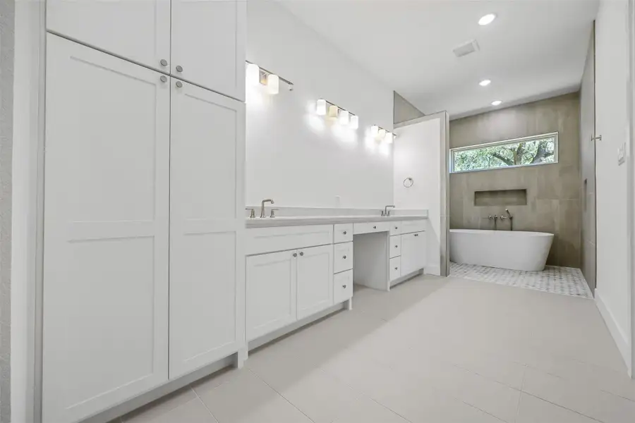Full bath with a freestanding bath, double vanity, tile patterned floors, and recessed lighting