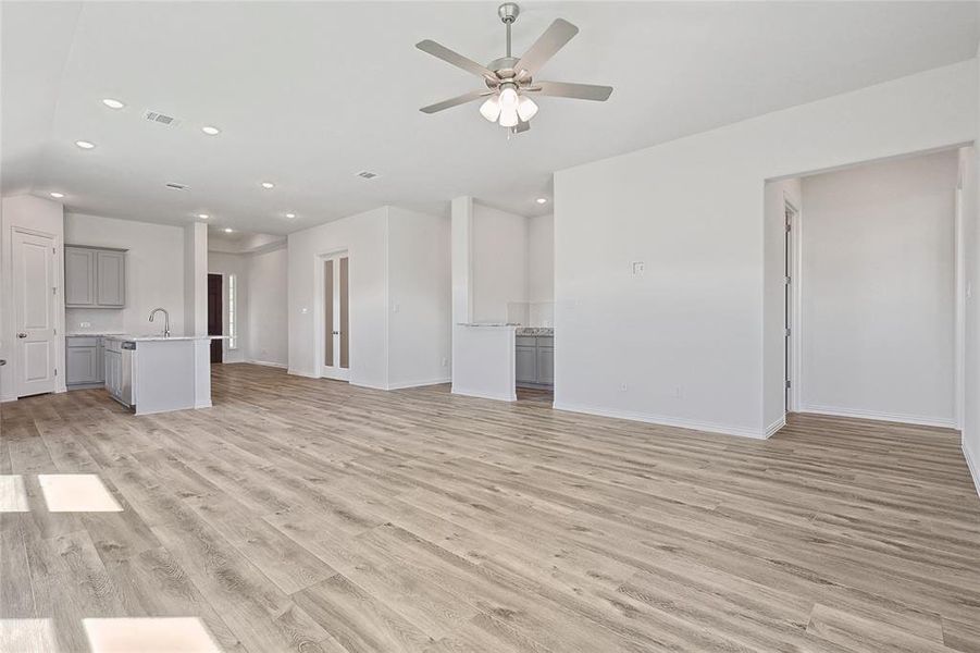 Unfurnished living room featuring ceiling fan, light hardwood / wood-style flooring, and sink