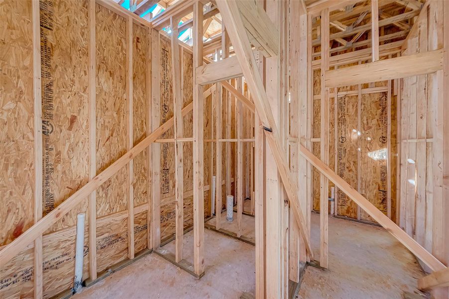 This photo shows a partially constructed interior with exposed wooden framing and plywood walls, indicating ongoing home construction.