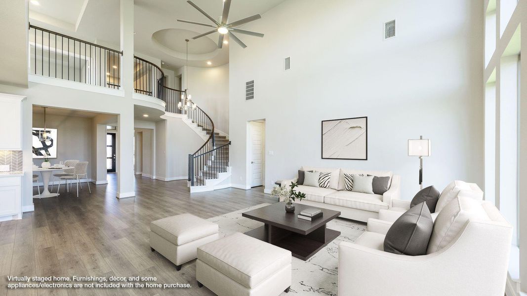 Living room featuring stairway, light wood finished floors, a ceiling fan, and a high ceiling Living room featuring stairway, light wood finished floors, a ceiling fan, and a high ceiling