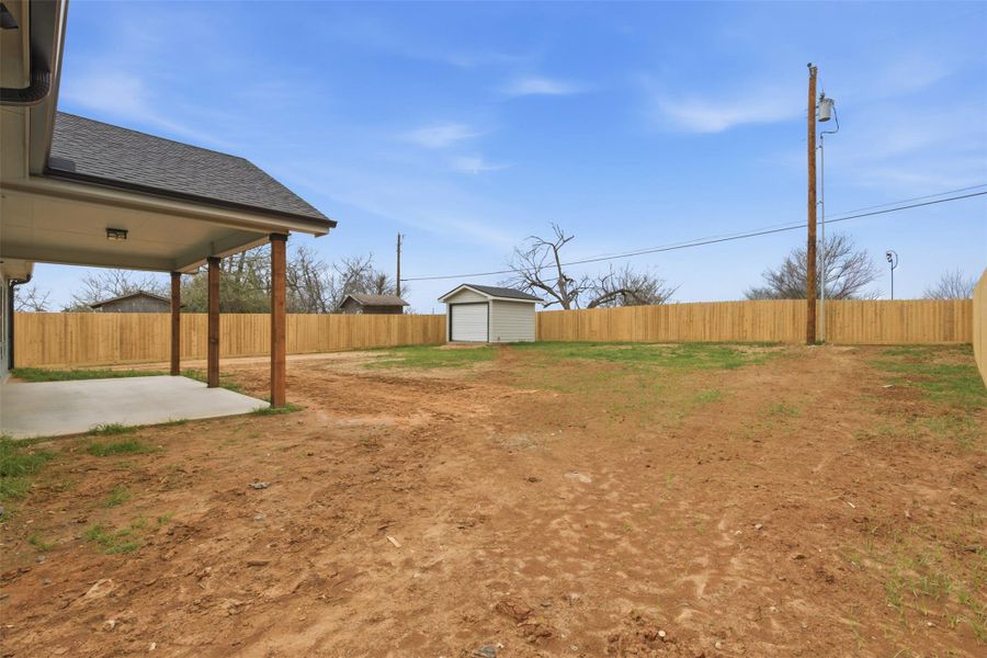 Fenced backyard with a patio and an outdoor structure